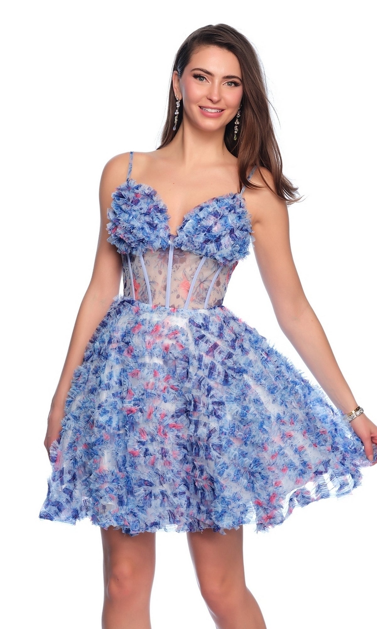 Smiling, she holds one side of her knee-length Dave and Johnny Short Blue Floral Hoco Dress 11768, a sleeveless style with a sheer bodice and delicate spaghetti straps.